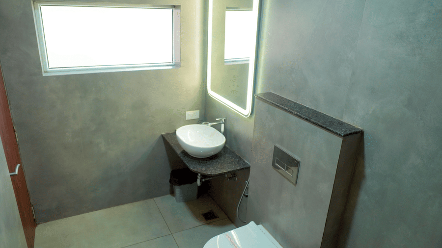 A bathroom view shows a toilet, a basin, a mirror, and a window at DNC Shevaroys Resorts and Spa.
