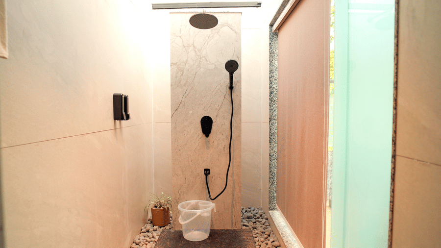 An outdoor shower area with a showerhead, a drain, and walls at DNC Shevaroys Resorts and Spa.