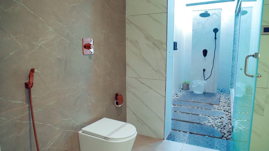 A bathroom with a toilet, a bidet shower, and an outdoor shower area at DNC Shevaroys Resorts and Spa.