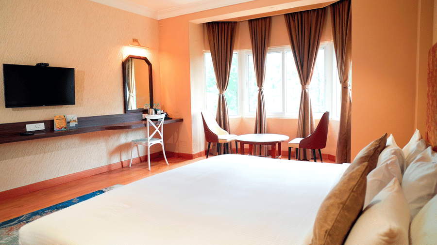A bedroom with a bed, curtains, and a mirror at DNC Shevaroys Resorts and Spa.