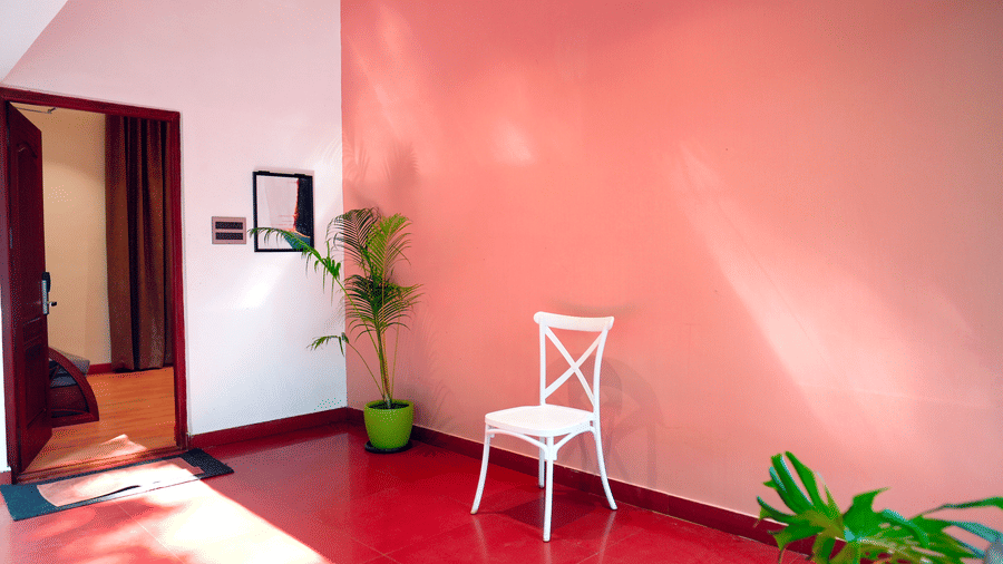 A villa entrance with a chair, plants, and a doorway at DNC Shevaroys Resorts and Spa.