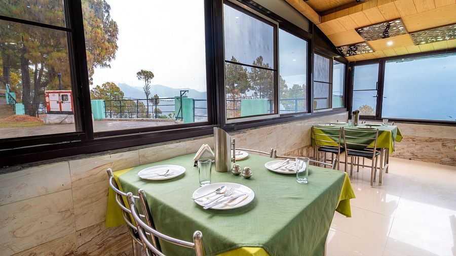 Tables with neatly places cutlery on it and a glass window overlooking the valleys at Flutter Hotels and Resorts, Lansdowne.