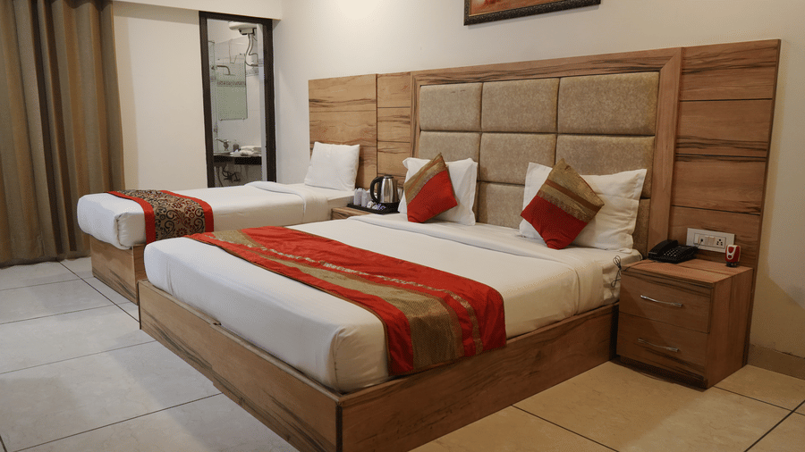 Hotel Exotic, Amritsar features a double bedroom with a wooden headboard, bedside tables, cushions and wall artwork.