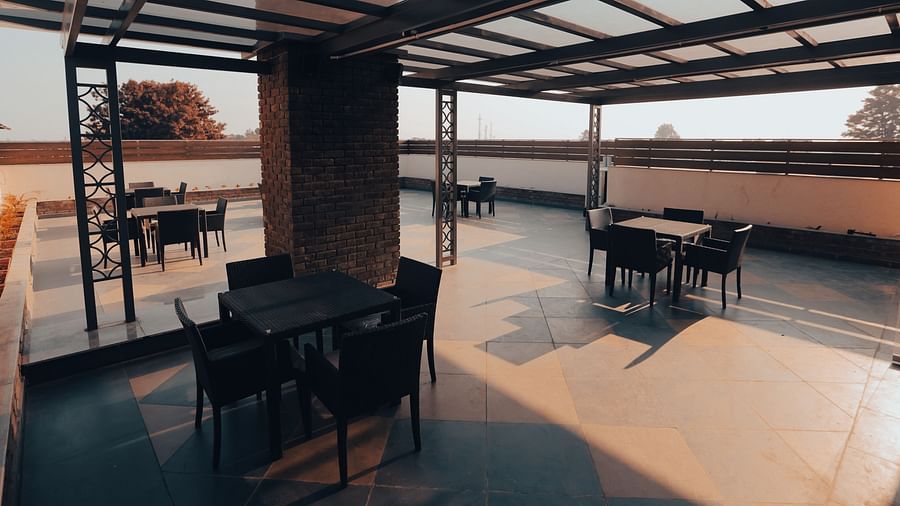 Clarks Inn Express Dehradun - view of the property s terrace with tables and chairs placed under a glass roof supported by a brick pillar