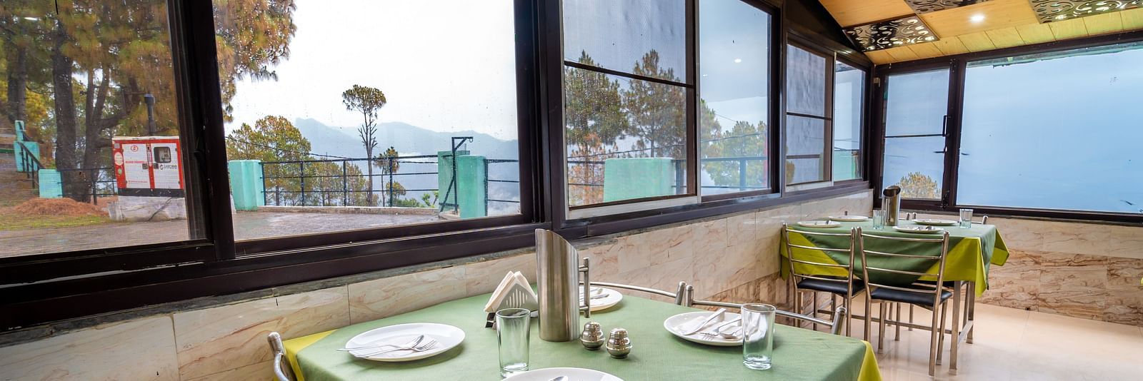 Tables with neatly places cutlery on it and a glass window overlooking the valleys at Flutter Hotels and Resorts, Lansdowne.