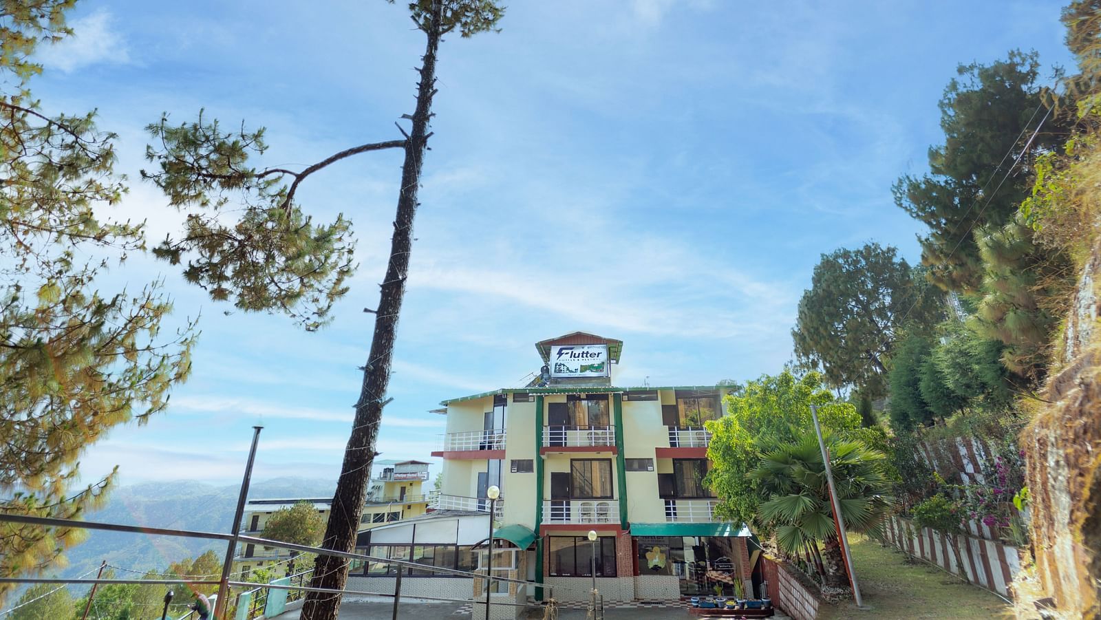 Facade of Flutter Hotels and Resorts, Lansdowne with trees and clear sky.