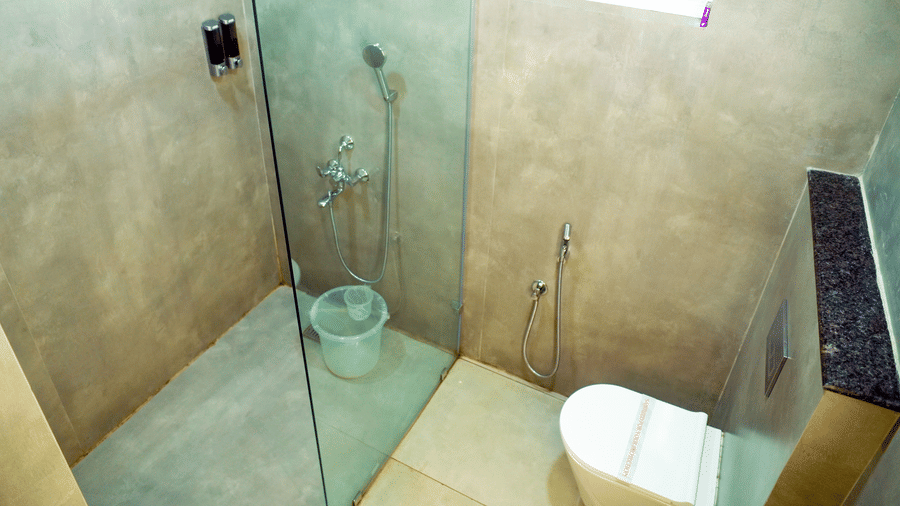A bathroom with a shower area, a toilet, and a sink at DNC Shevaroys Resorts and Spa.