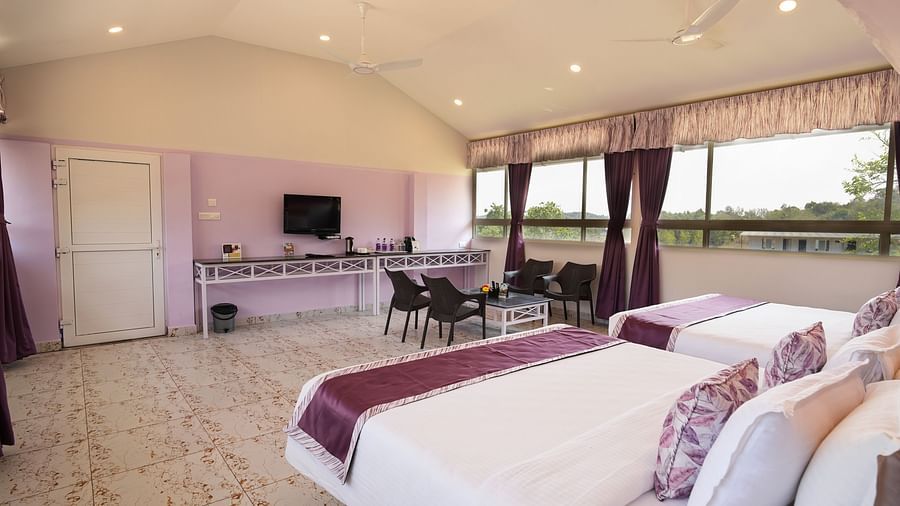 a large bedroom with small chairs and a mounted television - MGM Whispering Wind's, Yelagiri