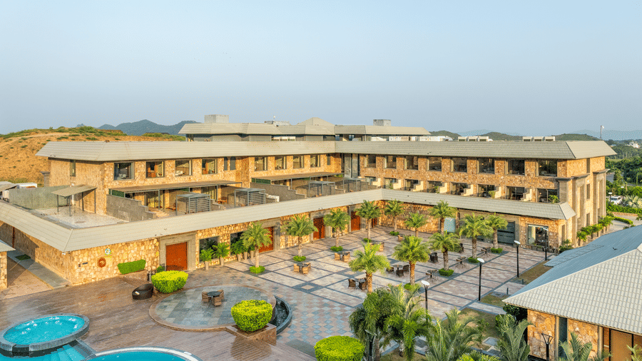 Central courtyard with swimming pool, palm trees, and elegant resort architecture at Pushkara Resort & Spa, Ajmer
