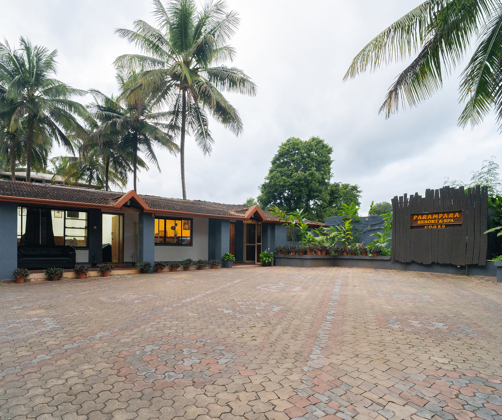 Facade of Parampara Resort & Spa, Coorg, Kushalnagar with trees surrounding it.