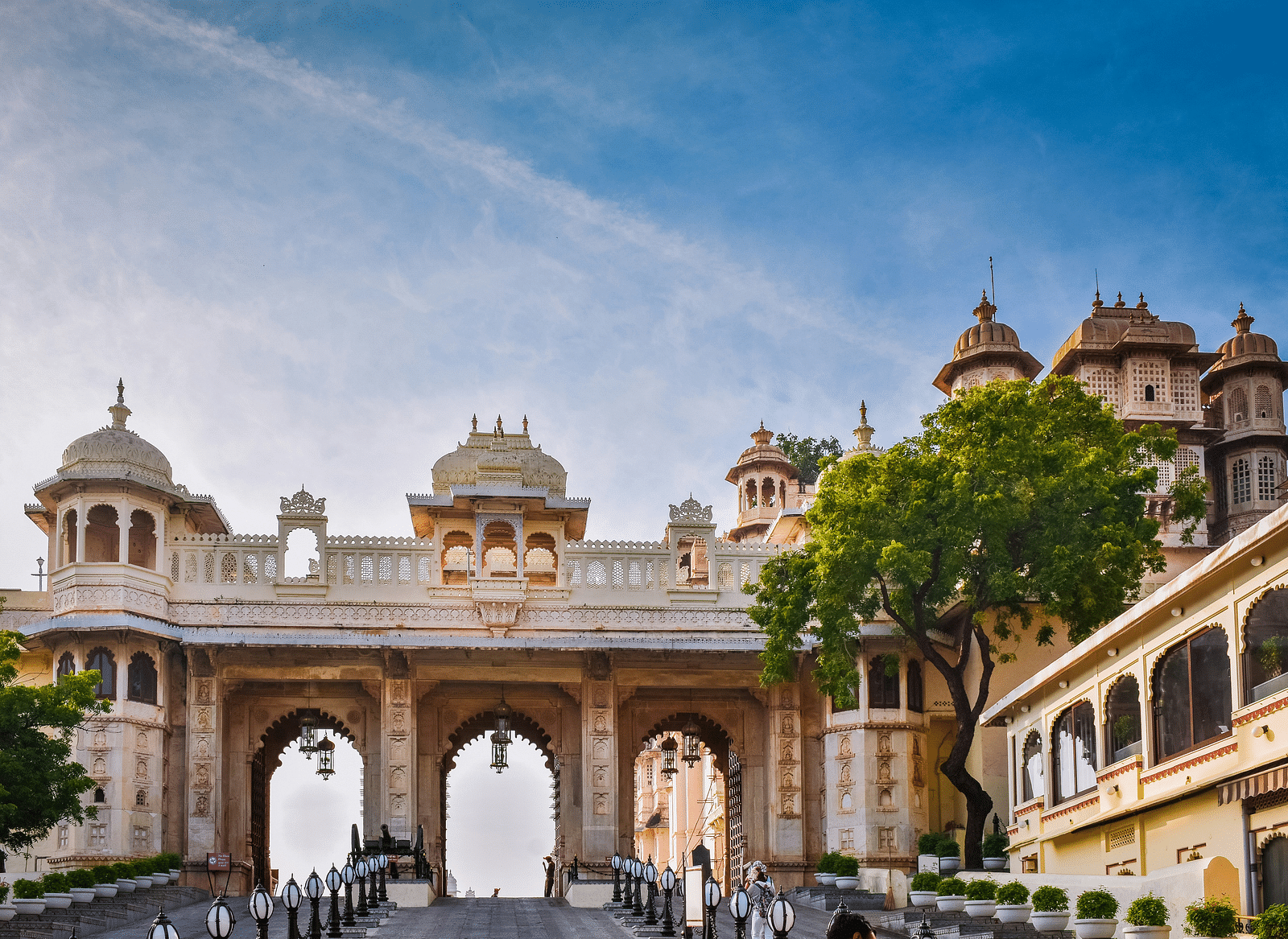 City Palace, Udaipur, Rajasthan, India, featuring arched gateways and domes under a blue sky.
