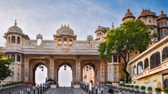 Ornate palace entrance with three large arches, surrounded by elegant architecture and lush greenery under a clear sky.