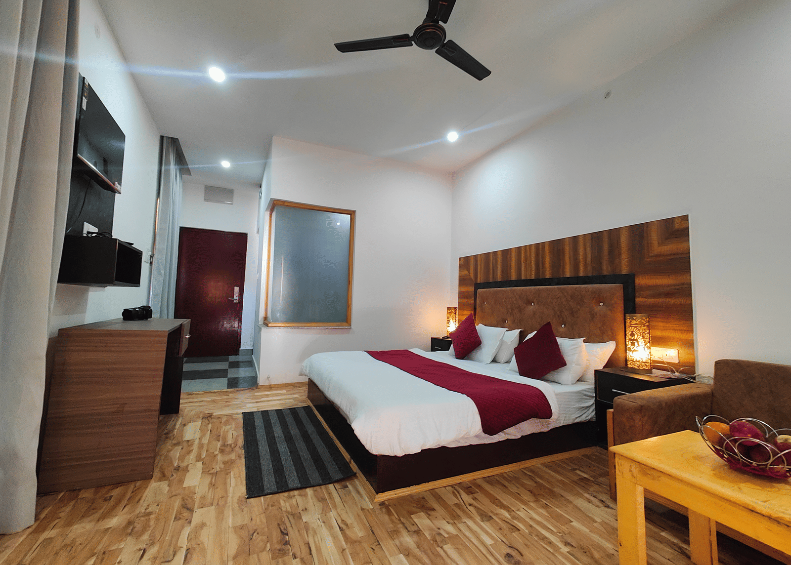 A well-furnished guest room with wooden flooring, a large bed, and warm lighting at Indus Serenity Retreat.