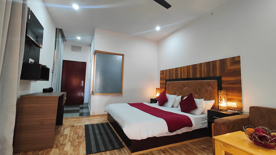 A well-furnished guest room with wooden flooring, a large bed, and warm lighting at Indus Serenity Retreat.