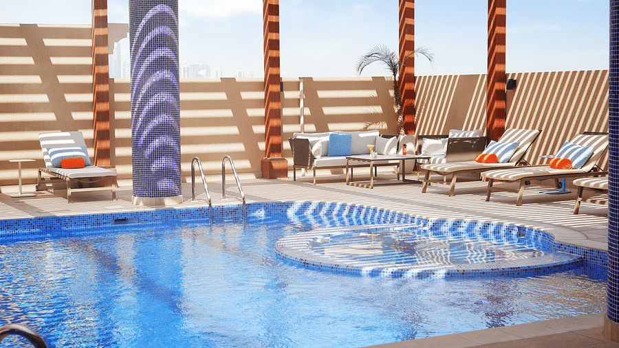 an overview of a swimming pool with loungers on the side - La Maison Hotel, Doha
