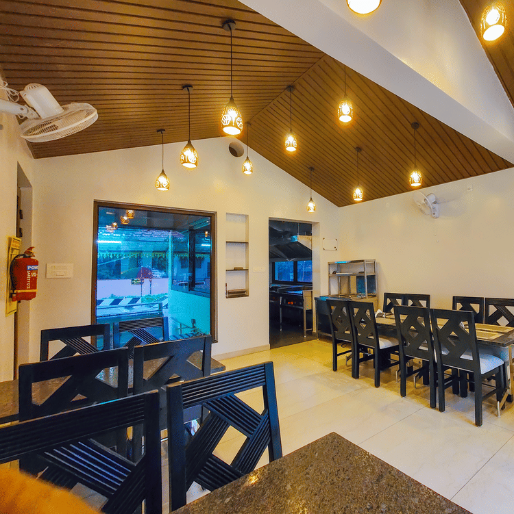 A brightly lit indoor dining area with wooden ceilings and neatly arranged tables - MGM Whispering Meadows