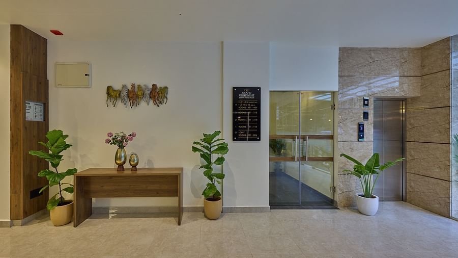 An image of an elevator in our hotel with a wall-mounted signboard beside the lift indicating the destinations of each floor and a small wooden table with a vase filled with flowers