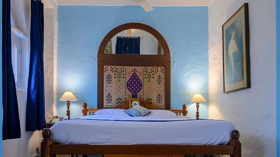 Hill Fort Kesroli 14th Century Alwar - interior view of the Sitara room with a king size bed and a painting on the wall