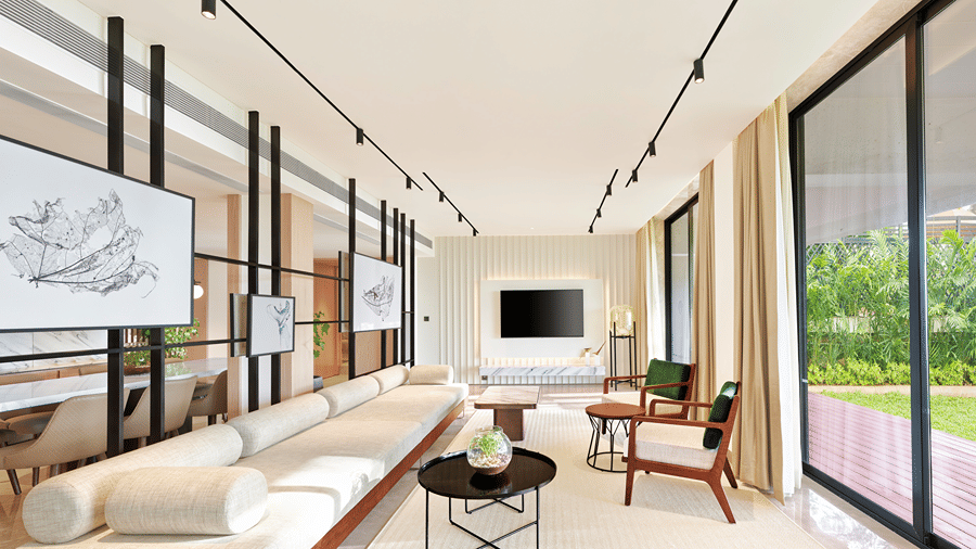 A long sofa with a tv wall mounted in the background and a floor to ceiling window opposite the sofa inside the Presidential Suite at The Resort, Mumbai.