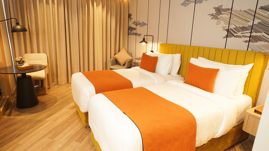 Twin beds with side table and curtains in a well-lit guest room - Ramada Encore by Wyndham Gurugram Dwarka Expressway