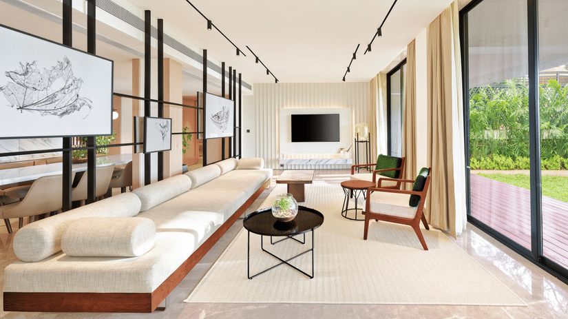 A long sofa with a tv wall mounted in the background and a floor to ceiling window opposite the sofa inside the Presidential Suite - The Resort, Mumbai