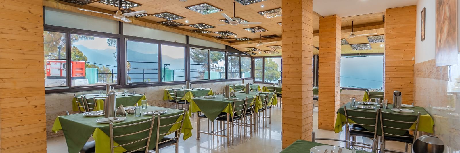 Dining area at Flutter Hotels and Resorts, Lansdowne with aligned chairs and table  and cutlery on them.