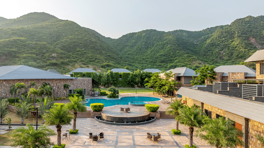 Aerial view of Pushkara Resort & Spa, Ajmer, surrounded by mountains with trees on the side of pathways