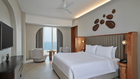 The Imperial suite bedroom at Swosti Premium Beach Resorts, Puri, with a large bed, a television on the wall, and a balcony view.