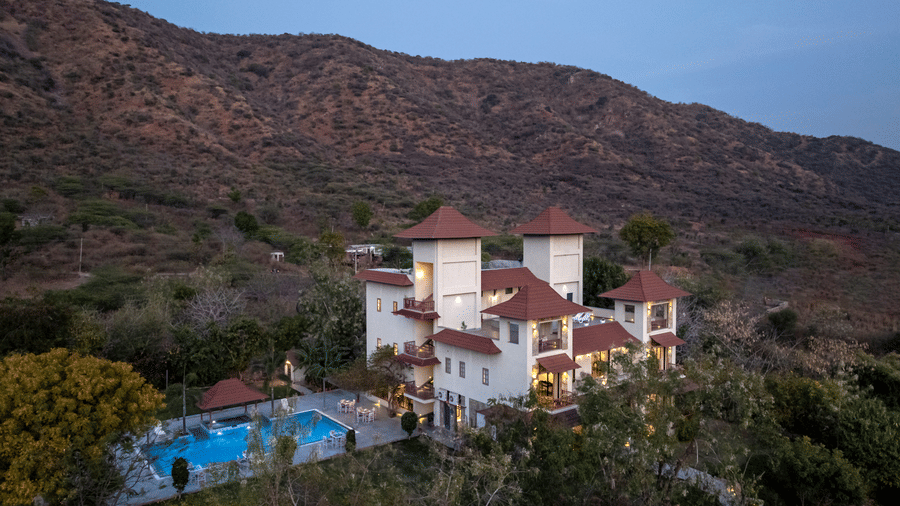 A birds' eye view of the The Hunting Lodge, Udaipur, showcasing the white-coloured facade surrounded by the desert jungle.