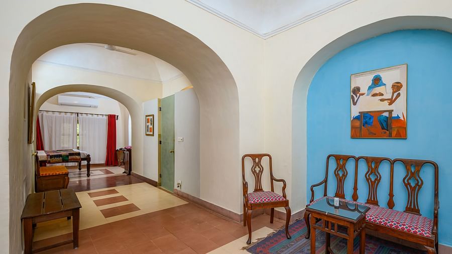 A hallway with arched doorways, seating, and artwork at Tijara Fort-Palace - 19th Century, Alwar.