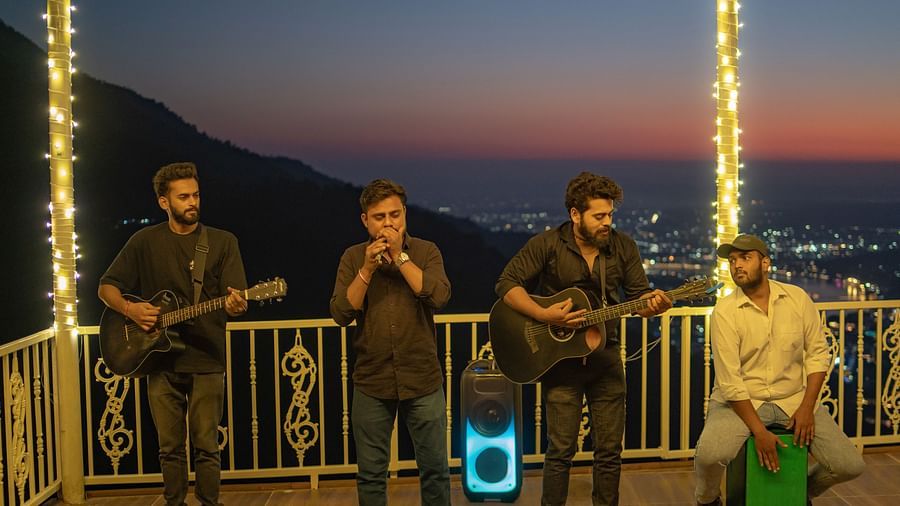 A wide-angle view of the rooftop area at Neer Ganga after sunset, with live music creating a vibrant atmosphere. where people are playing different instrument and singing song at Neer ganga.