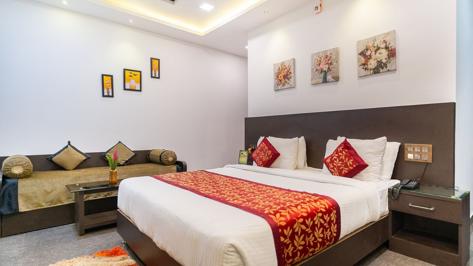 Image of a room with a bed and three flower prints above the bed at Parampara Resort & Spa, Kushalnagar.