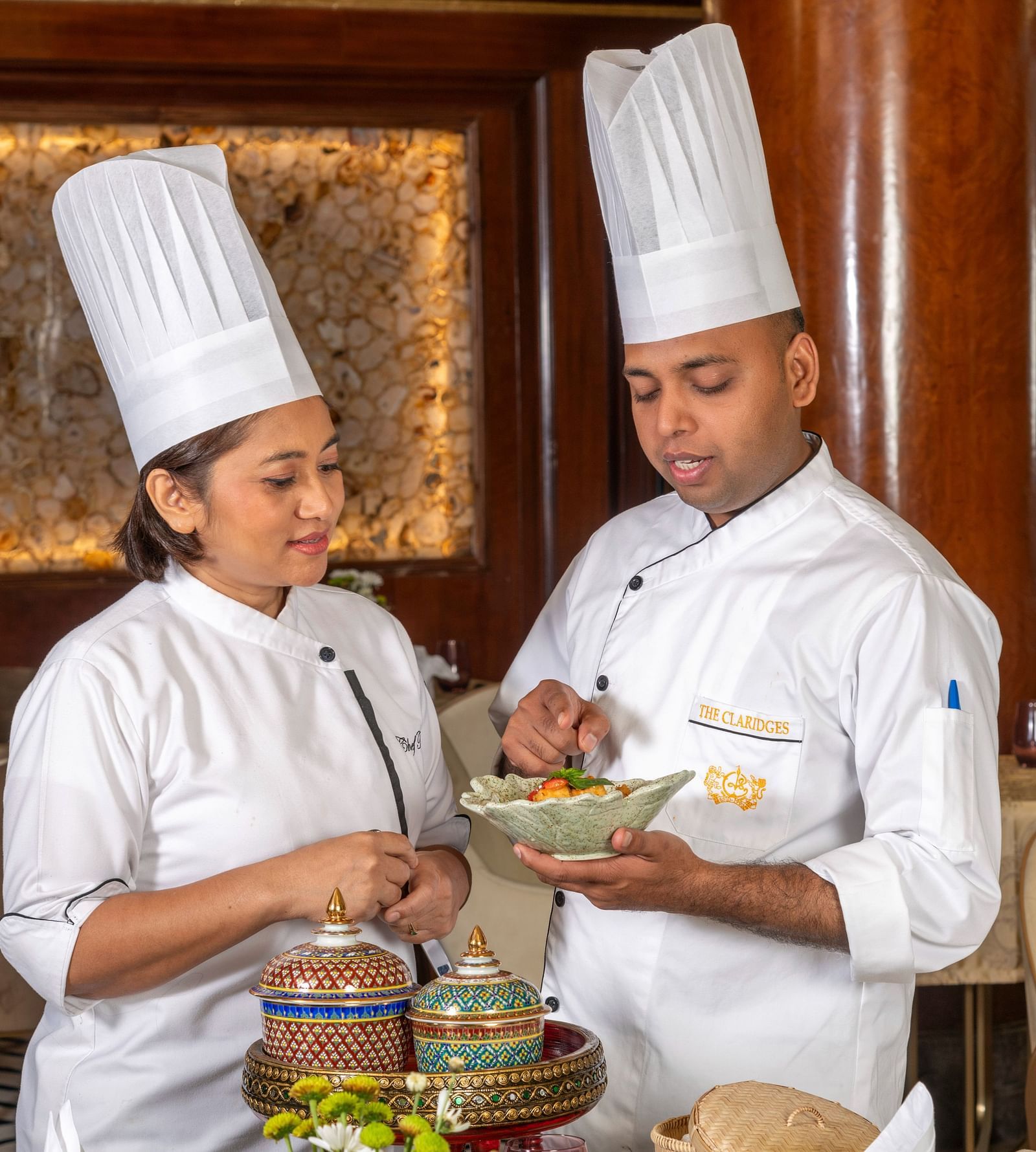 An image of two chefs with one chef holding a bowl of delicious food - Claridges Collection