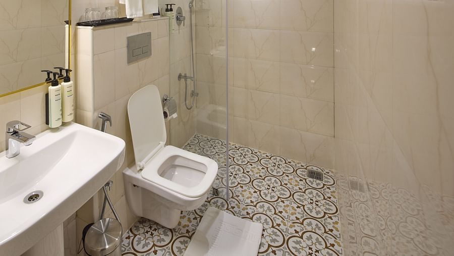 A hotel restroom with a sink, commode, separate shower area, and tiled flooring - Grand Continent, Brookefield