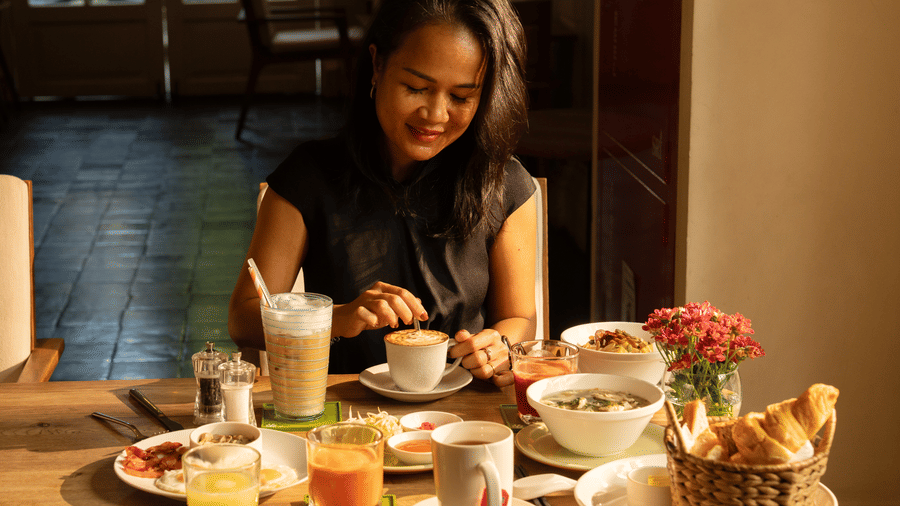 Guest enjoying a breakfast spread with coffee, juice, and freshly prepared dishes at Central Mansions, Phnom Penh.