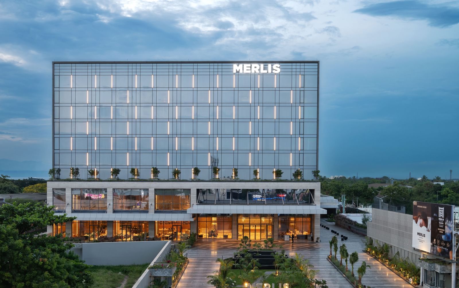 Full exterior view of the hotel building during twilight, showcasing its modern design at Merlis Hotel, Coimbatore.