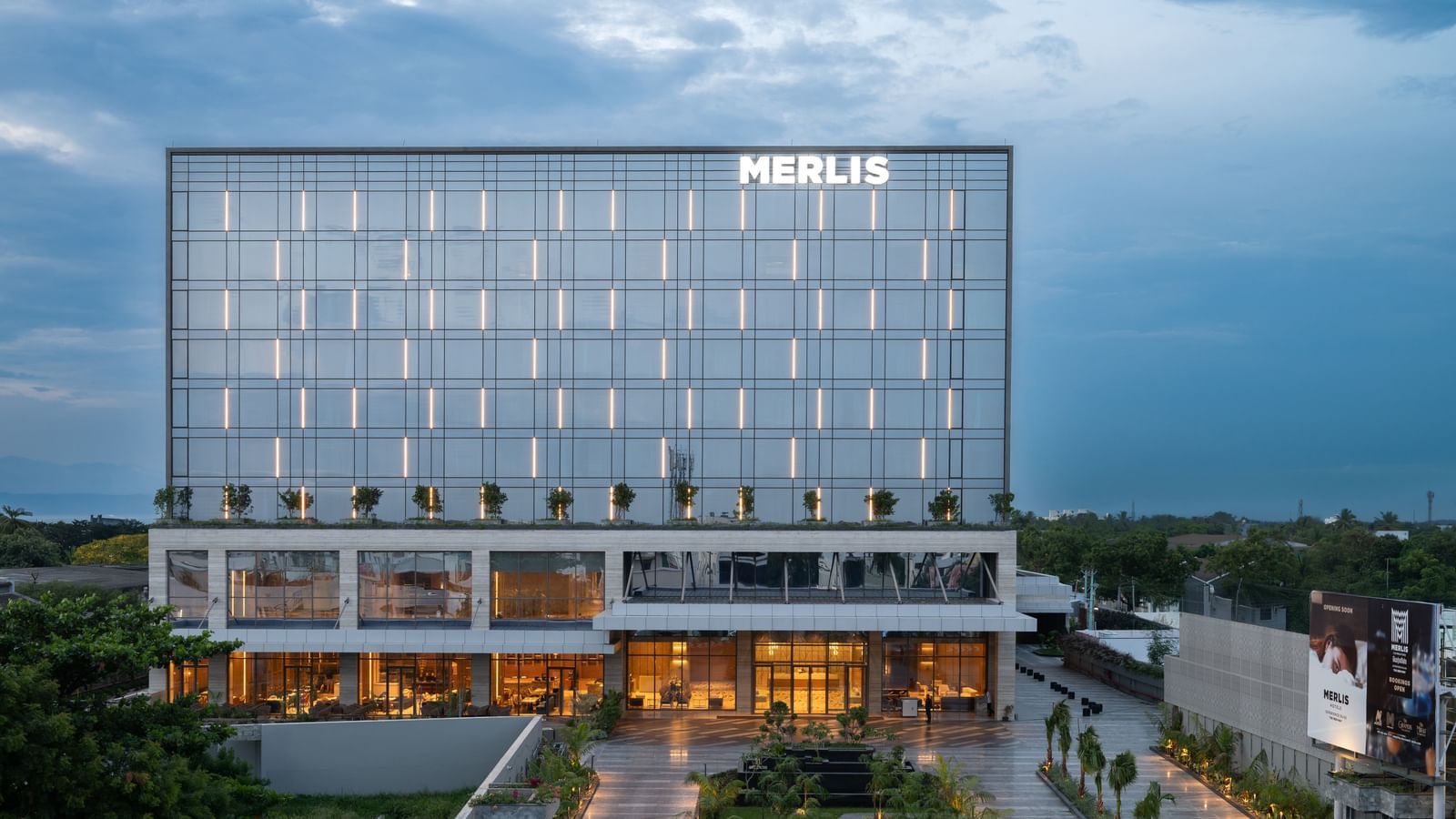 Full exterior view of the hotel building during twilight, showcasing its modern design at Merlis Hotel, the best 5-star hotel in Coimbatore.