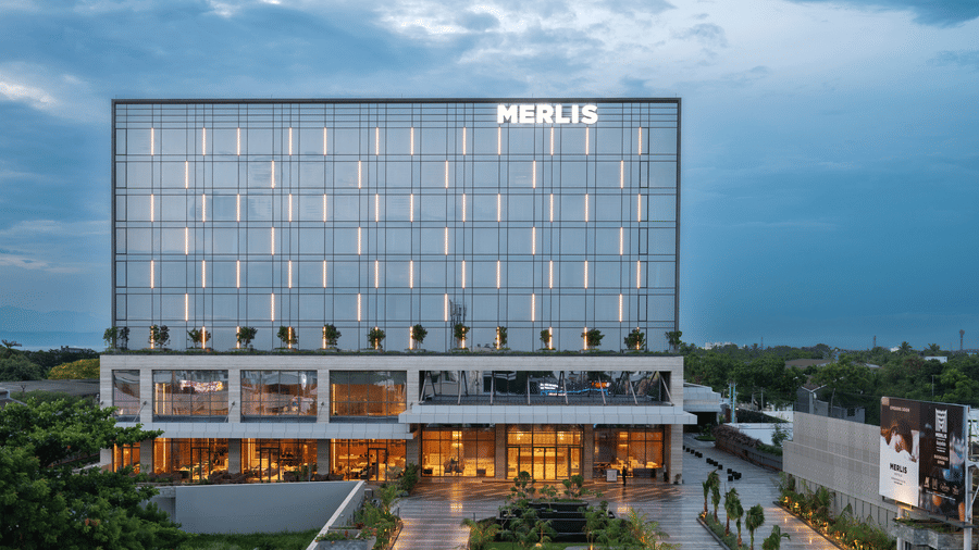 Full exterior view of the hotel building during twilight, showcasing its modern design at Merlis Hotel, the best 5-star hotel in Coimbatore.