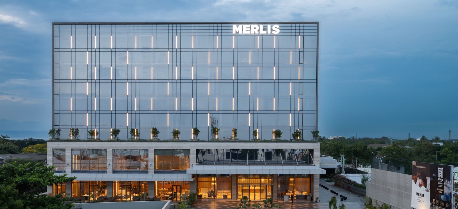 Full exterior view of the hotel building during twilight, showcasing its modern design at Merlis Hotel, the best 5-star hotel in Coimbatore.
