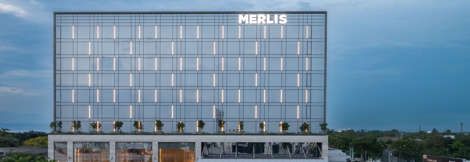 Full exterior view of the hotel building during twilight, showcasing its modern design at Merlis Hotel, the best 5-star hotel in Coimbatore.