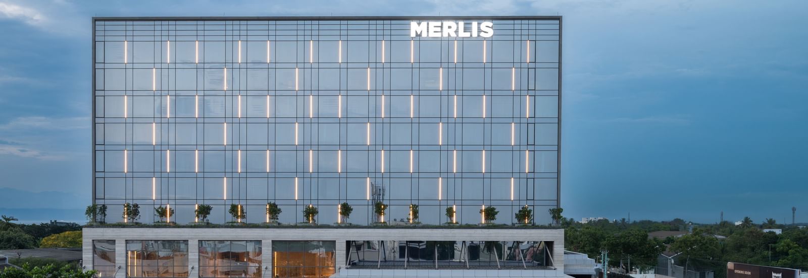 Full exterior view of the hotel building during twilight, showcasing its modern design at Merlis Hotel, the best 5-star hotel in Coimbatore.