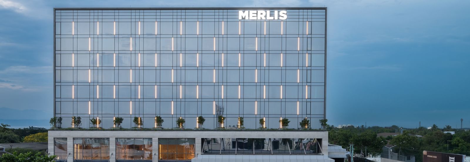 Full exterior view of the hotel building during twilight, showcasing its modern design at Merlis Hotel, the best 5-star hotel in Coimbatore.