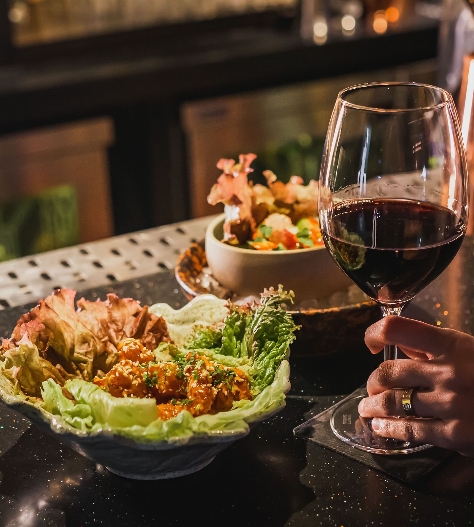 image of a person holding a glass of wine along with a delicious serving on the table at The Claridges New Delhi