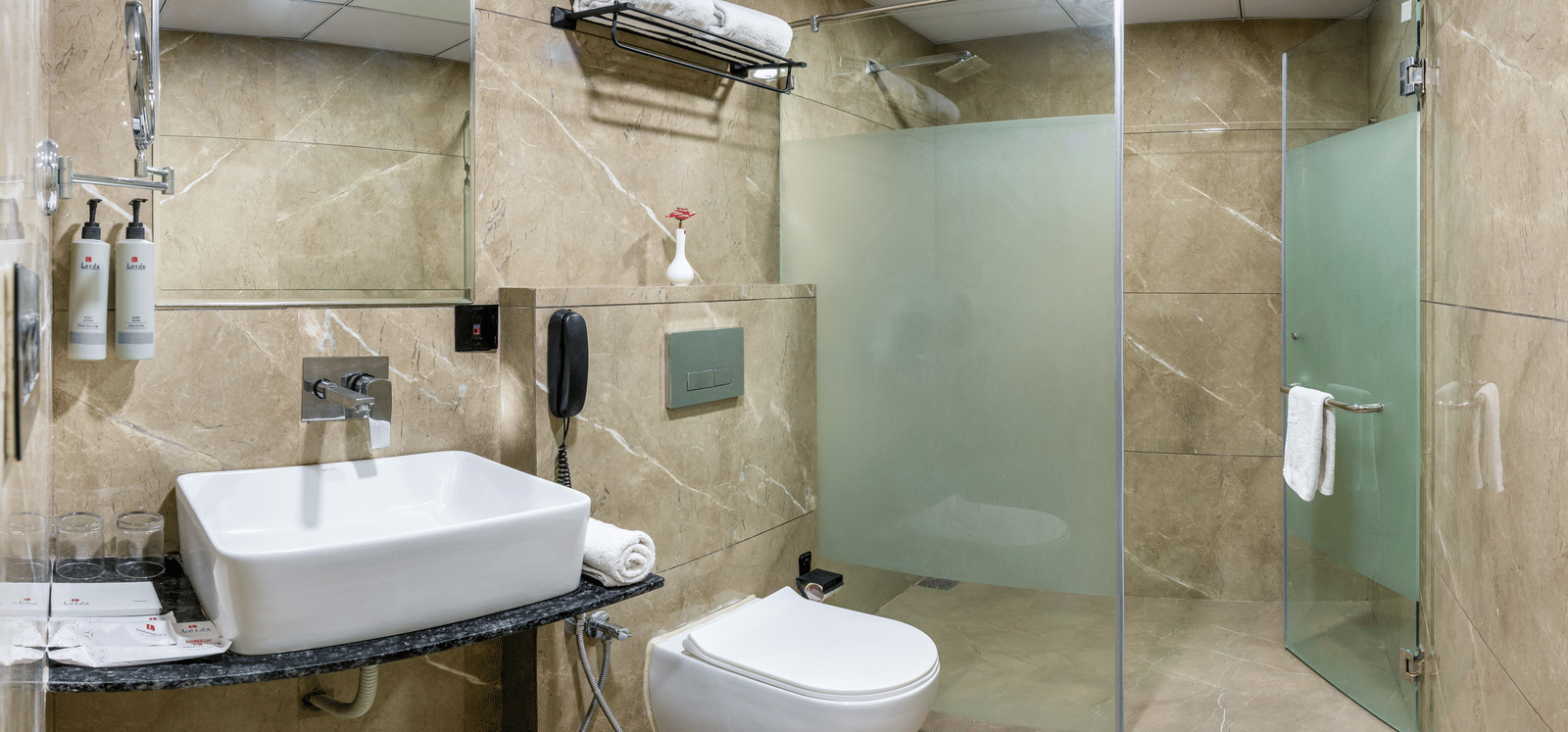 Clean bathroom with shower enclosure, washbasin, and modern amenities at Lords Studio Inn, Jamnagar.