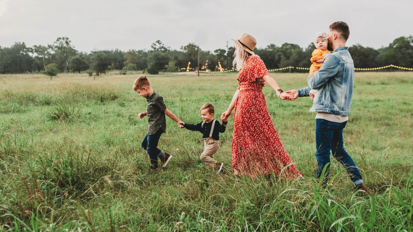 A group of people walk in a field, and two children accompanying.