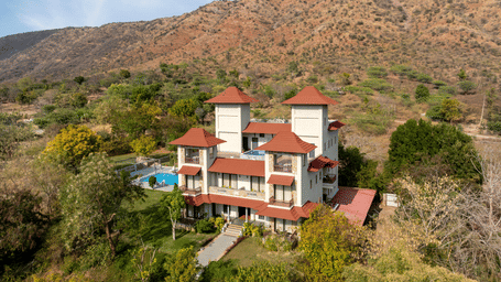 A birds' eye view of the exterior of The Hunting Lodge, Udaipur, surrounded by desert jungles and the Aravallis in the background.