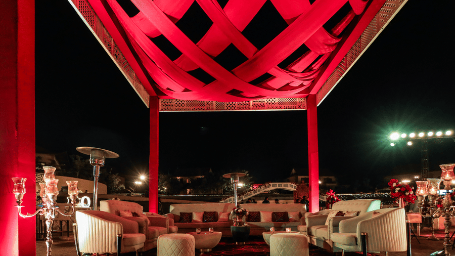 A seating area under a large overhead structure with chairs and tables at Ananta Spa and Resort, Jaipur