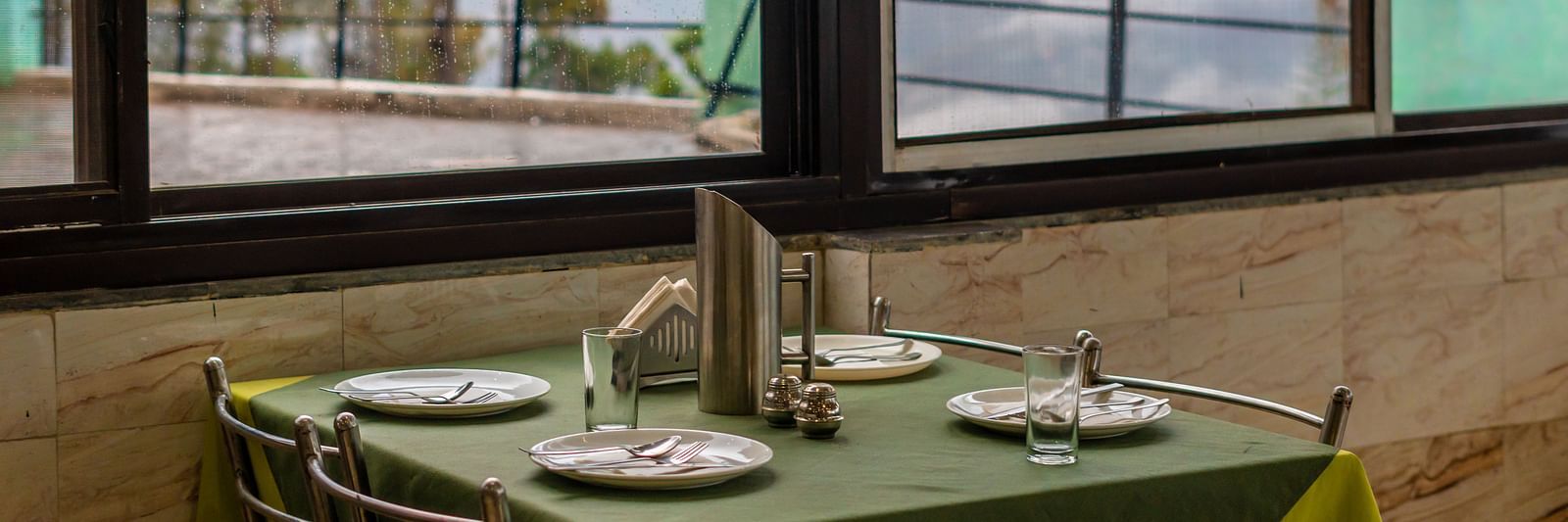 A table with neatly places cutlery on it and a glass window overlooking the valleys at Flutter Hotels and Resorts, Lansdowne.
