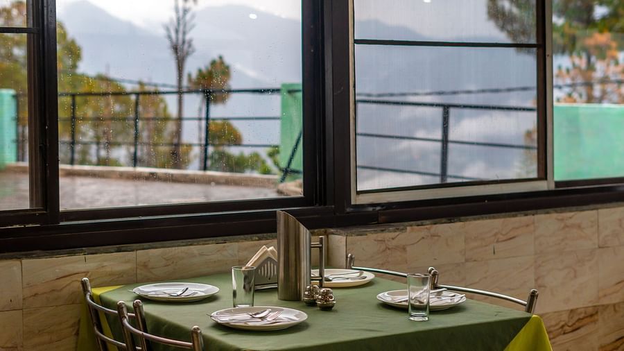 A table with neatly places cutlery on it and a glass window overlooking the valleys at Flutter Hotels and Resorts, Lansdowne.