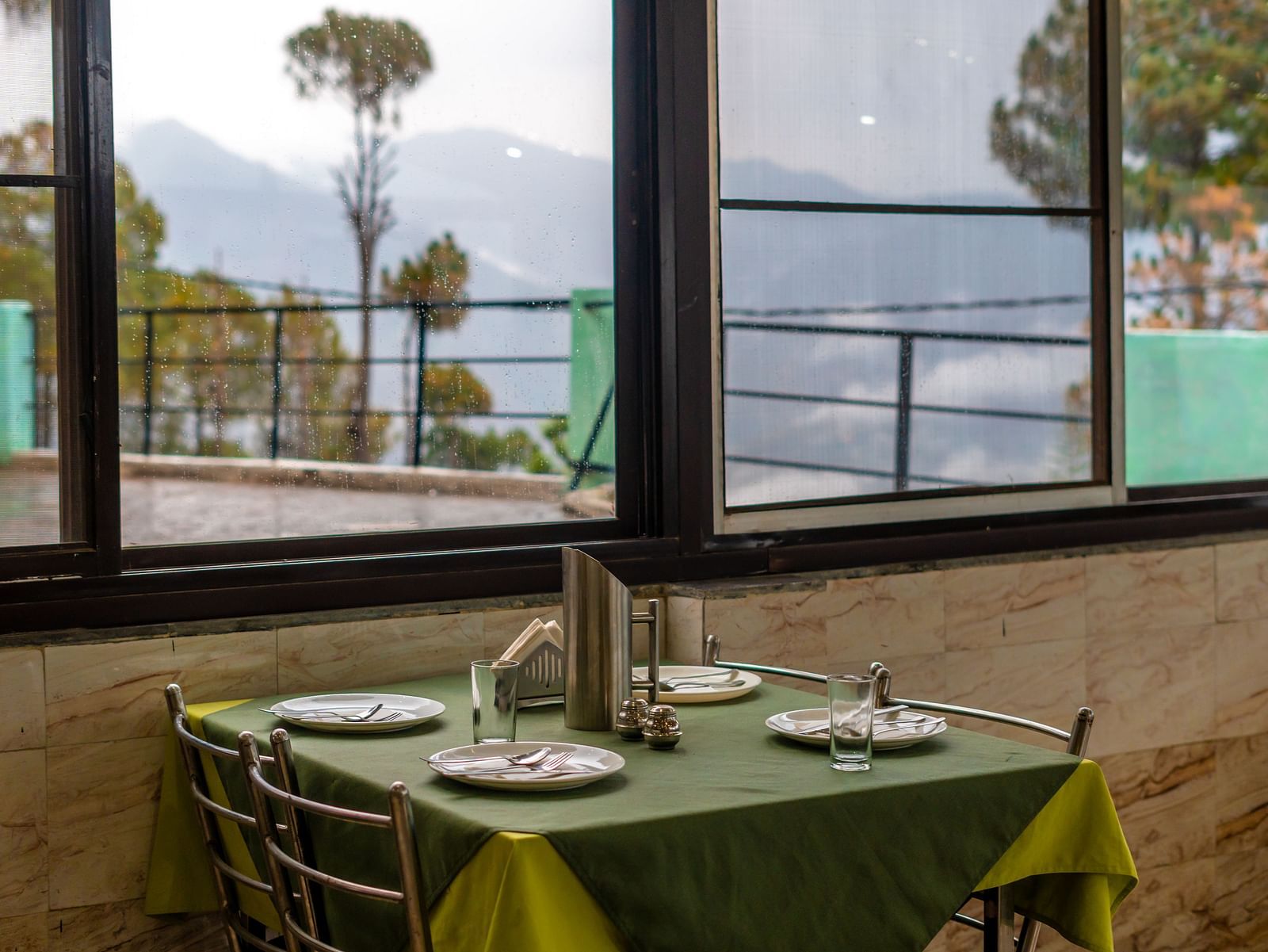 A table with neatly places cutlery on it and a glass window overlooking the valleys at Flutter Hotels and Resorts, Lansdowne.
